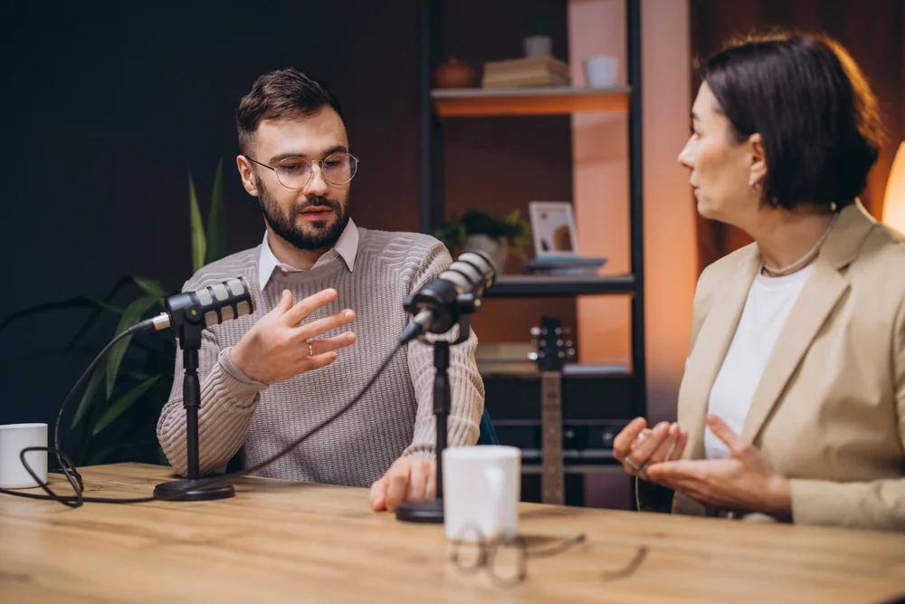 Two guests recording a podcast episode with professional microphones