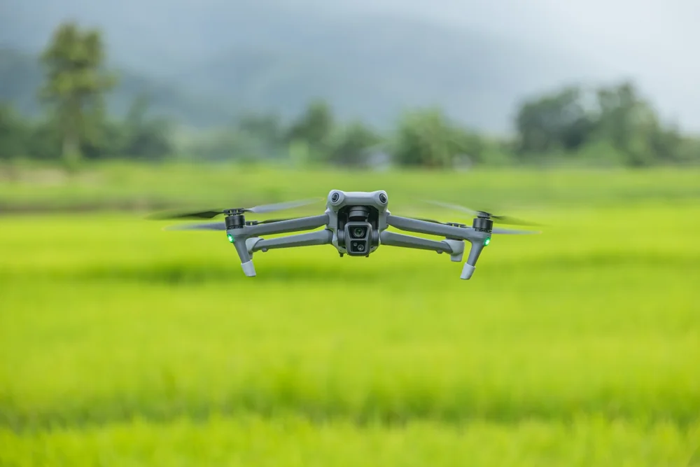 Small drone flying low over a green agricultural field